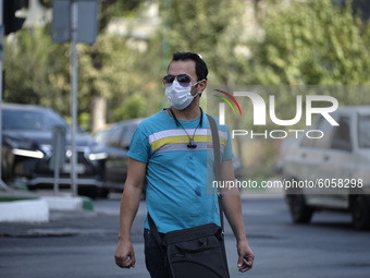 An Iranian man wearing a protective face mask looks on as he crosses an avenue in central Tehran while the new coronavirus (COVID-19) diseas...