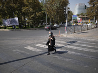 An Iranian woman wearing a protective face mask crosses an avenue in northern Tehran while the new coronavirus (COVID-19) disease rapid risi...