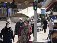 Iranian people wearing protective face masks cross an avenue in northern Tehran while the new coronavirus (COVID-19) disease rapid rising in...