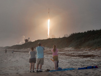 Spectators watch from Canaveral National Seashore as a SpaceX Falcon 9 rocket carrying 60 Starlink satellites launches from pad 39A at the K...