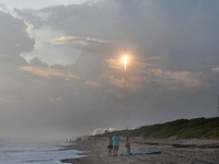 Spectators watch from Canaveral National Seashore as a SpaceX Falcon 9 rocket carrying 60 Starlink satellites launches from pad 39A at the K...