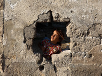 A Palestinian girl looks through a hole in the wall outside her family home in Al-Shati refugee camp in Gaza City on October 8, 2020.
 (
