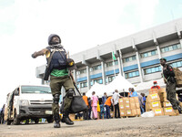 Police officers walk past officials of the Independent National Electoral Commission while distributing the electoral sensitive materials to...