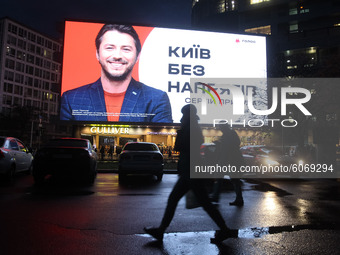 People walk next to a screen of a shopping mall that displays an election campaign advertisement of Serhiy Prytula a candidate for the post...