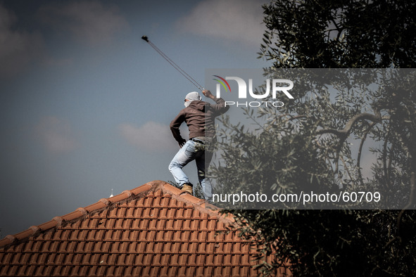 A Palestinian protester uses a sling to hurl stones towards Israeli soldiers during a protest against the Jewish settlement of Ofra, in the...