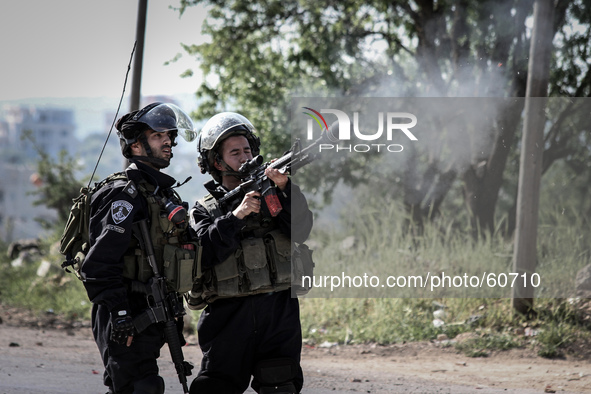A member of the Israeli forces shooting  a tear gas boom at Palestinian stone throwers (unseen) during clashes in the West Bank village of S...