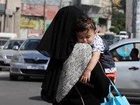A Palestinian woman holds a sleeping baby as she walks in a street, amid the coronavirus disease (COVID-19) outbreak,in Gaza City, on Octobe...
