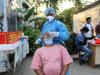 A health worker in personal protective equipment (PPE) collects a nasal swab samples from homeless people for Covid-19 Rapid Antigen Testing...
