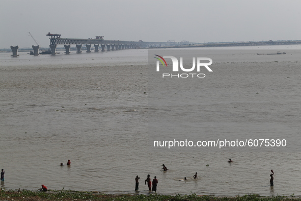 Villagers bathe on the Padma River as a multipurpose road-rail bridge under construction across the Padma River at Mawa, near Dhaka, Banglad...