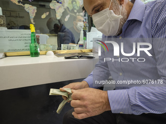 An Iranian man counts U.S. Dollar banknotes as he sits in a currency exchange shop in Tehran’s business district on October 10, 2020. U.S. D...