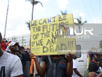 Youth of ENDSARS protesters display a placard in a crowd in support of the ongoing protest against the harassment, killings and brutality of...