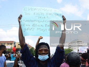 Youth of ENDSARS protesters display a placard in a crowd in support of the ongoing protest against the harassment, killings and brutality of...