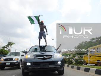 Youth of ENDSARS protesters display the Nigerian flag on top a car showing his support to the ongoing protest against the harassment, killin...
