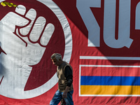 A lonely man walks through the streets of Stepanakert, capital of Nagorno Karabakh, under a huge banner with the Armenia flag on October 13,...