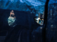 A Palestinian woman wearing a protective mask walks behind a curtain, on a street, amid the coronavirus disease (COVID-19) outbreak in Gaza...