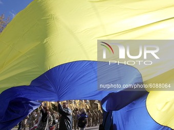 Ukrainians wave a large Ukrainian flag during a march to the 78th anniversary of the founding of the Ukrainian Insurgent Army in central Kyi...
