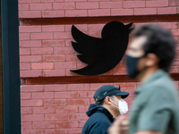 A view of people on masks, walking past the Twitter logo at their New York City headquarters on October 14, 2020. Facebook And Twitter Limit...
