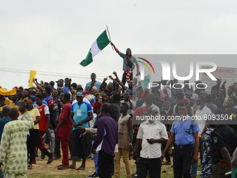 A Youth of End Sars Protesters hold a Nigerian National flag admits crowds to barricade the Lagos - Ibadan expressway, the oldest highway an...