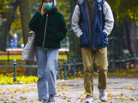 young people wear face masks while walking through the Planty park during coronavirus pandemic. Krakow, Poland on October 16th, 2020. Due to...