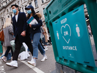 A couple wearing face masks cross Oxford Circus, past a social distancing notice, in London, England, on October 16, 2020. London is to be p...