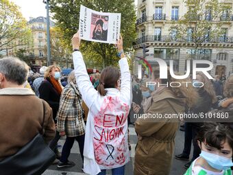 A woman wearing a blood-stained blouse holds a copy of the satirical newspaper Charlie Hebdoas people gather on Place de la Republique in Pa...