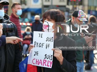 A  woman holds a placard reading « I’m a teacher, I’m Charlie » as people gather on Place de la Republique in Paris on October 18, 2020, in...