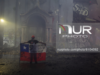 A Person holds the Chilean flag just in front of the church of San Borja, after being burned down and destroyed.   
In the midst of commemo...