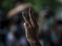 Protesters are seen holding up the 3-flinger salute the symbol for Thailand's protest at the building where the Royal Thai Consulate General...