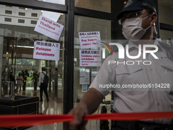 A Police officers stands guard in front of placards placed on the window of the building where the Royal Thai Consulate General of Hong Kong...