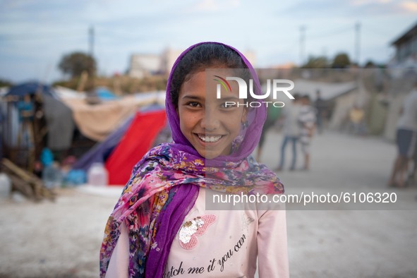 A smiling girl with a headscarf at the roof of a building where she lived after the fire. Portraits of young children refugees, minors boys...