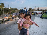 Siblings posing for a picture at the roof of a building where they lived after the fire of Moria camp. Portraits of young children refugees,...