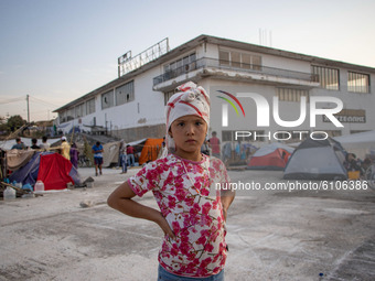 A little girl from Afghanistan posing at the roof of a building where she is living. Portraits of young children refugees, minors boys and g...