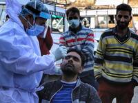 A medical worker collects a swab sample from a commercial Driver for a Rapid Antigen Test (RAT) for the Covid-19 coronavirus, in Sopore, Dis...