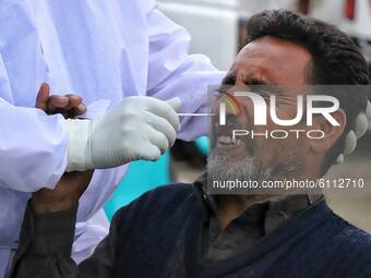 A medical worker collects a swab sample from a commercial Driver for a Rapid Antigen Test (RAT) for the Covid-19 coronavirus, in Sopore, Dis...