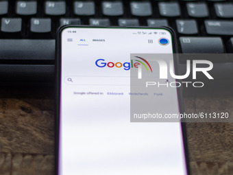 Google closeup logo displayed on a phone screen, smartphone on a keyboard is seen in this multiple exposure illustration, the company's symb...