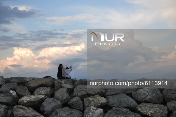 A couple takes a photo together above the construction of a breakwater embankment, in Besusu Village, Palu City, Central Sulawesi, Indonesia...
