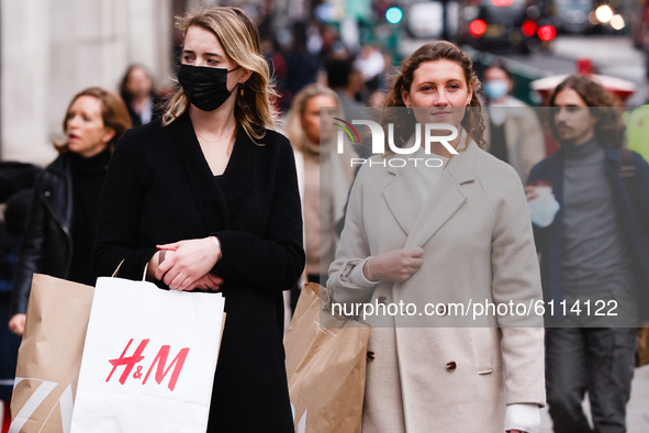 A woman wearing a face mask waits with bags of clothes shopping at a pedestrian crossing on Regent Street in London, England, on October 22,...
