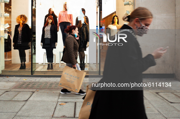 Women carrying bags from fast-fashion retailer Primark walk past a clothes store on Oxford Street in London, England, on October 22, 2020. R...