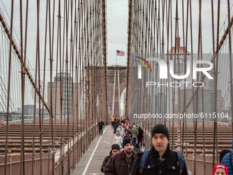 Hundreds of people on the Brooklyn Bridge in New York City in the United States as seen during a cloudy day with tourists and locals on it....