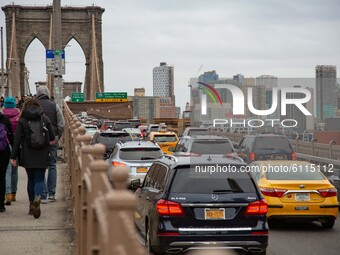 People among them many tourists and traffic with cars from Brooklyn Bridge in New York City in the United States as seen during a cloudy day...