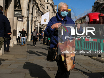 People walk wearing a protective face mask in Regent Street, London on October 23, 2020.  (
