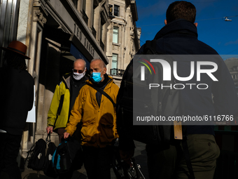 People walk wearing a protective face mask in Regent Street, London on October 23, 2020.  (
