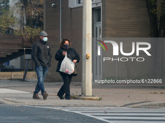 People wearing face masks while walking along the street during the novel coronavirus (COVID-19) pandemic in Toronto, Ontario, Canada on Oct...