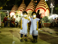 Twin sister come to the temple with their parent to celebrate Durga Puja, the biggest religious festival of the Bengali Hindu community, has...