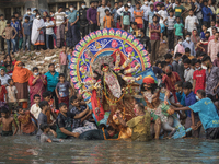 Hindu devotees immerse an idol of the Hindu goddess Durga in the Buriganga river during the final day of Durga Puja festival in Dhaka on Oct...
