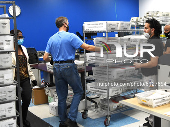Michael Duve (from L), Bruno Morini, and Angel Alvira prepare mail-in ballots for loading into a sorting machine at the Orange County Superv...