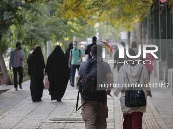 An Iranian man and his female social friend (R) who does not cover her hairs with scarf, walk along a street-side in Tehran’s business distr...