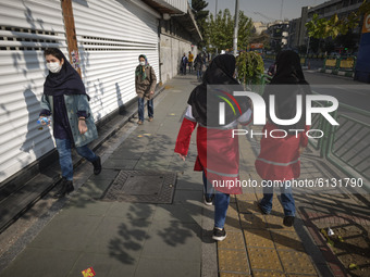 Two female members of Iran Red Crescent Society (R) walk along a street-side while looking for people who may not use protective face masks,...