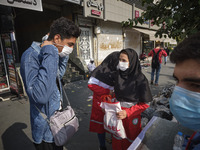 A female member of Iran Red Crescent Society explains a man how to wear a protective face mask to prevent himself of infection by the new co...