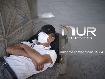 An Iranian man wearing a protective face mask rests out of the City Theatre building in central Tehran amid the new coronavirus disease (COV...